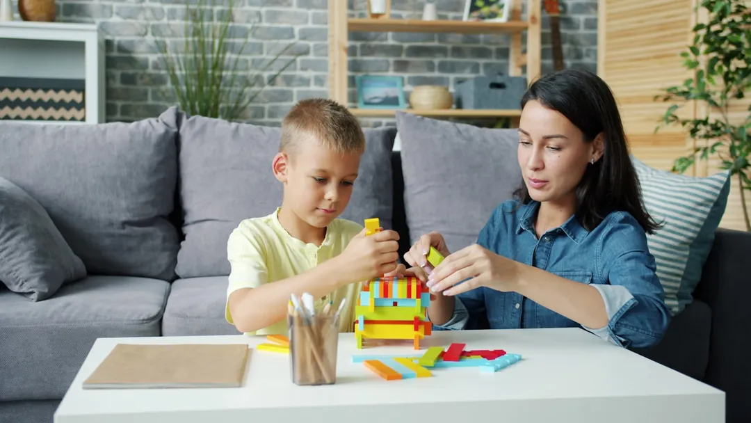 A therapist and a child building together with colourful blocks