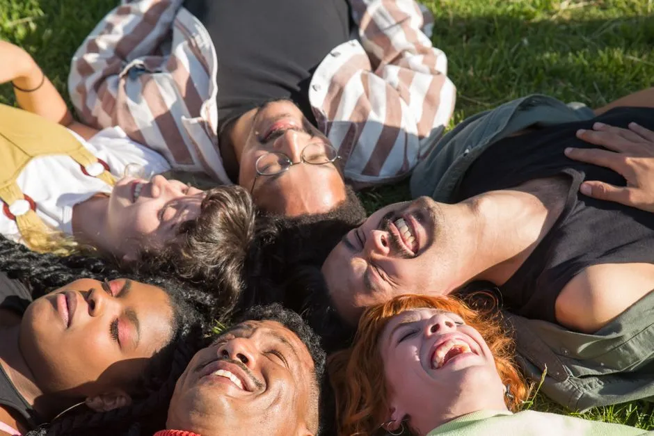A group of people lying in the grass together, laughing